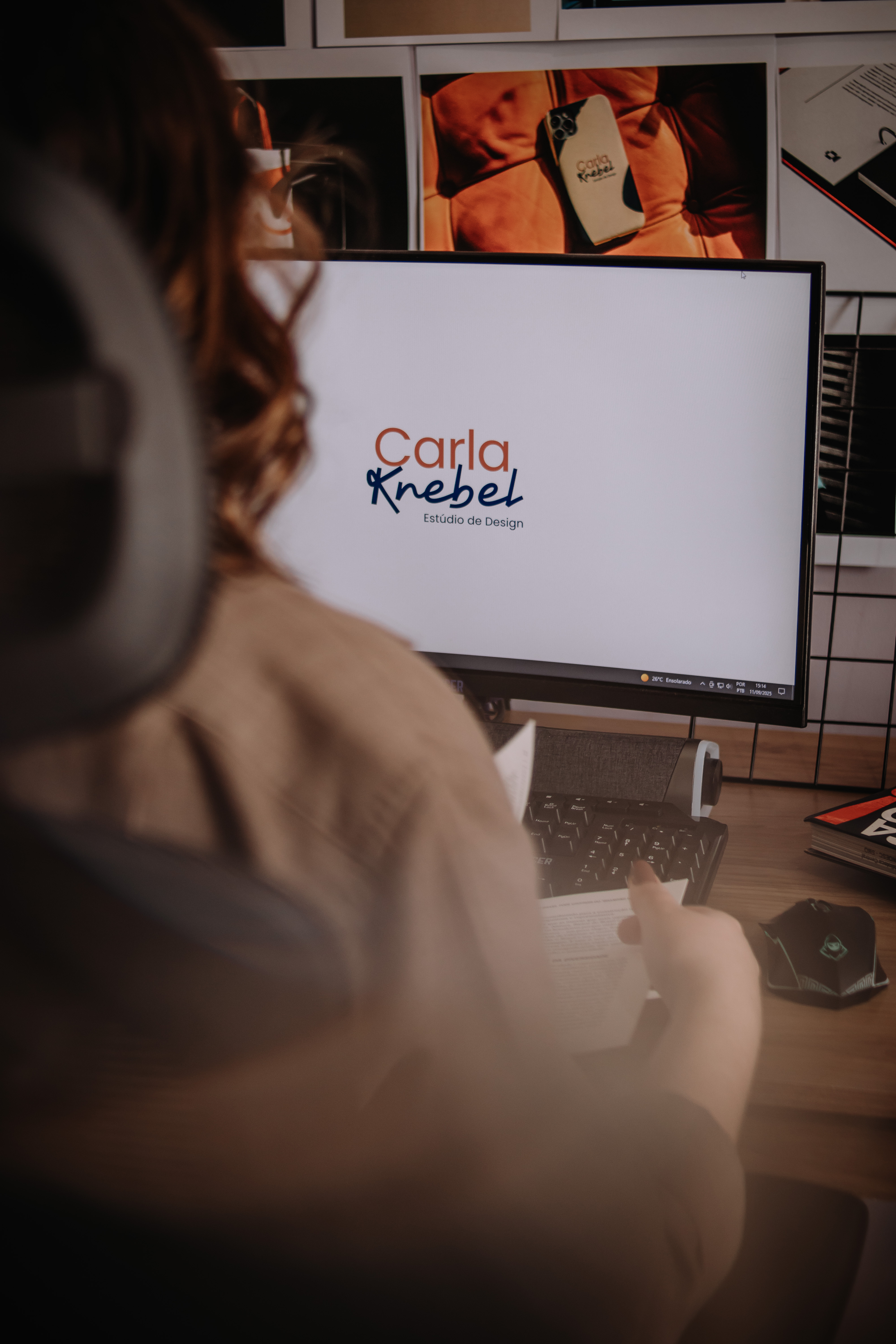 Carla Knebel com portfólio de projetos na parede